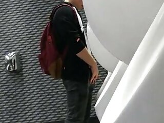 A male student is pissing in the toilet.